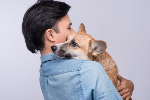 young man carrying his mixed breed dog